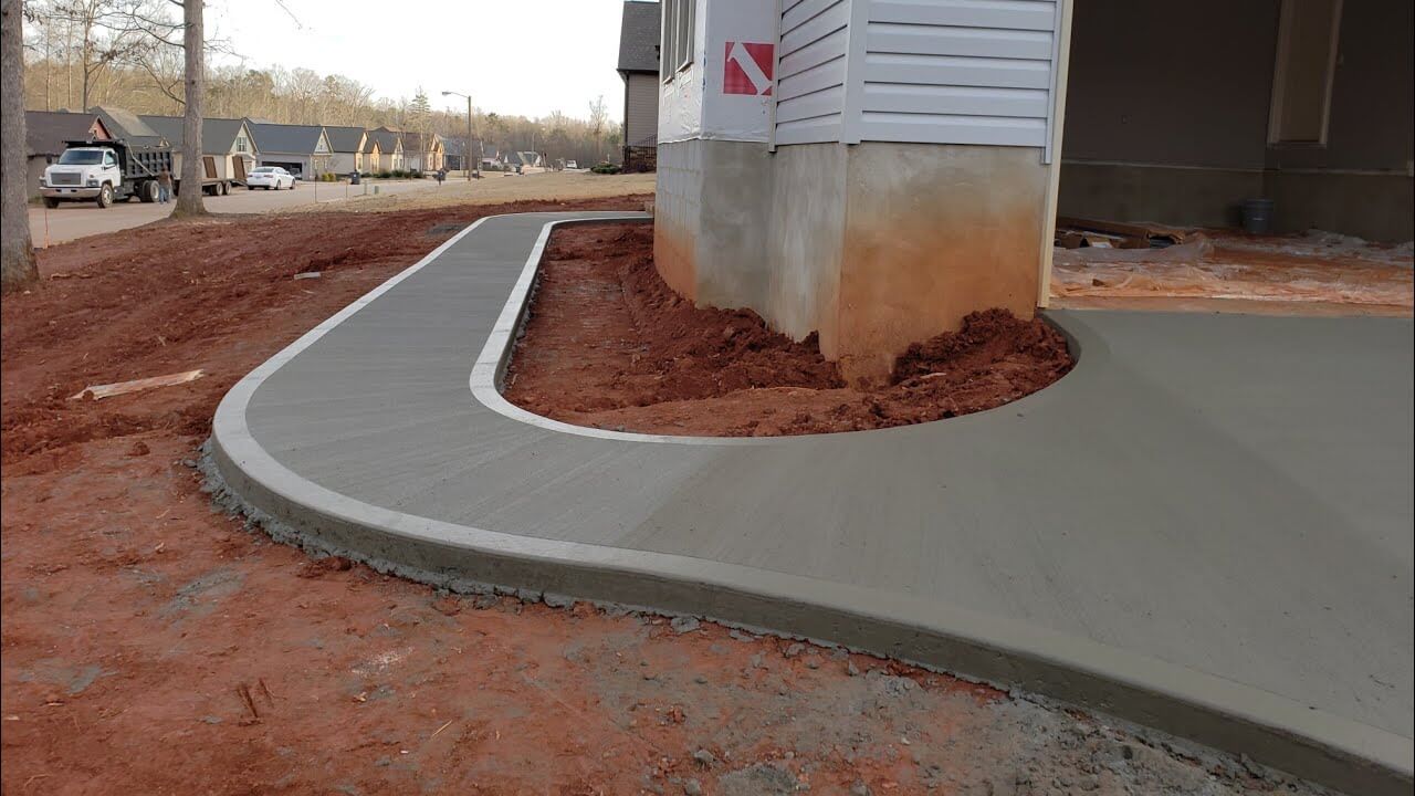 New concrete sidewalk and driveway to a house 