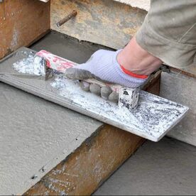 A man hand leveling a concrete step that is freshly poured