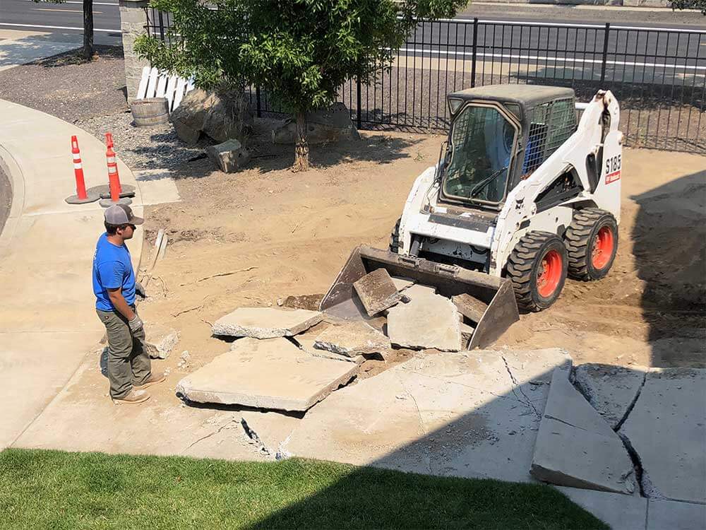 A skid steer removing and replacing a concrete driveway